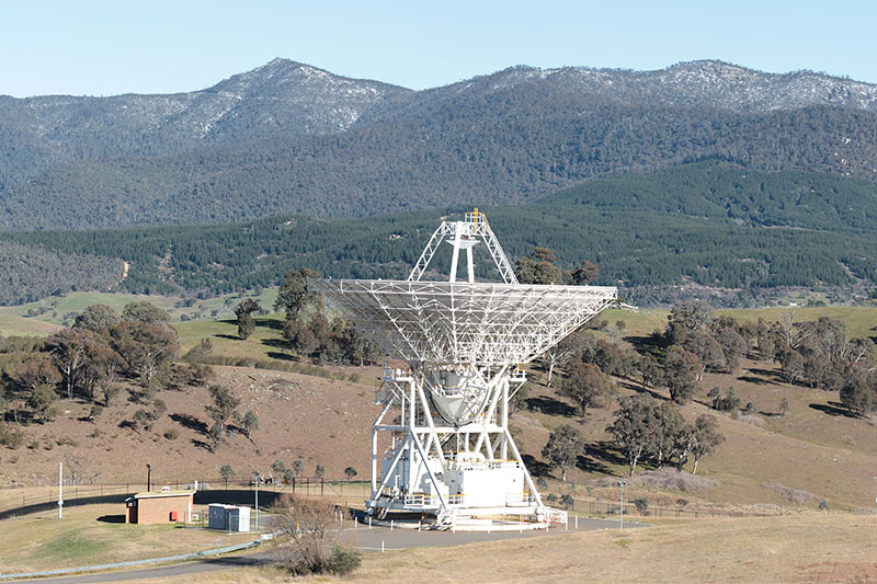Deep Space Station 45 facing straight up in front of hills dotted with snow