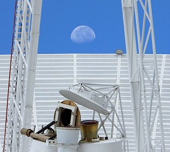 Feed horns, quad legs and dish of Deep Space Station 43 with the Moon