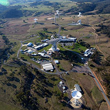 Aerial view of the Canberra Deep Space Communication Complex, showing six antennas and buildings.