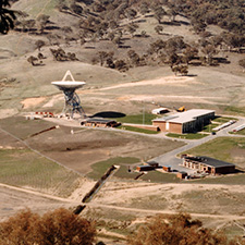 Wide aerial view showing Deep Space Station 42 facing up from a distance plus some buildings and roads.