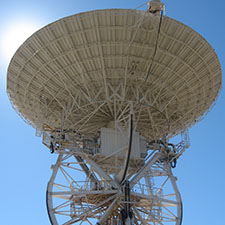 Closer view of Deep Space Station 46 facing straight up with a blue sky and the Sun peaking over the left hand edge of the dish.