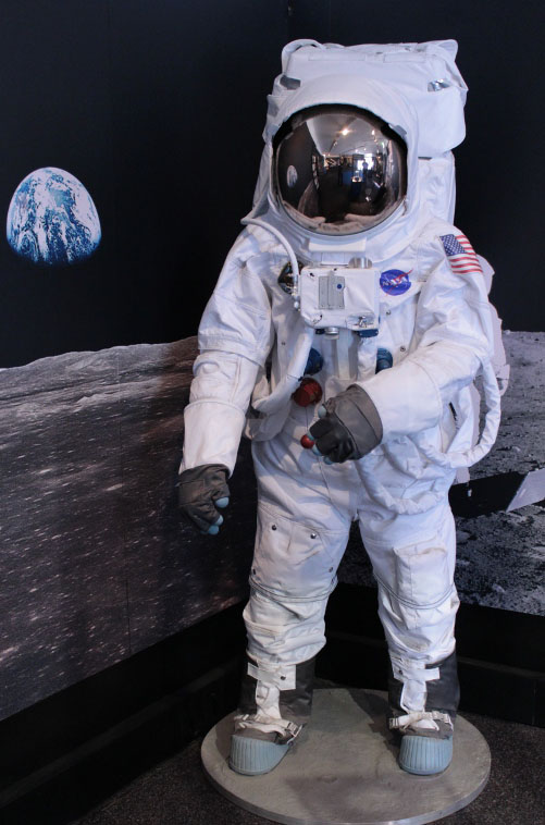 Spacesuit with helmet closed beside a picture of the Earth from the Moon